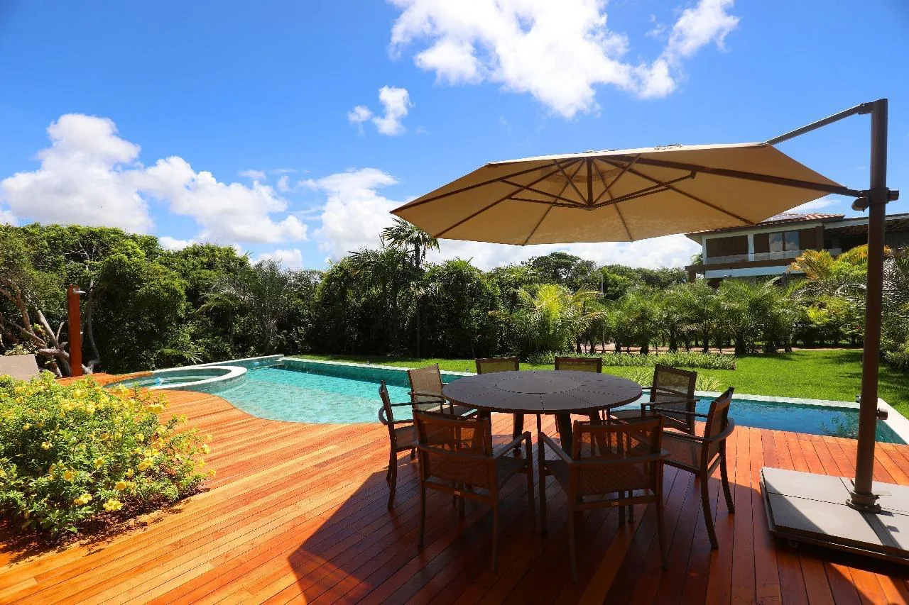 Deck da piscina com mesa de jantar e guarda-sol, ao ar livre