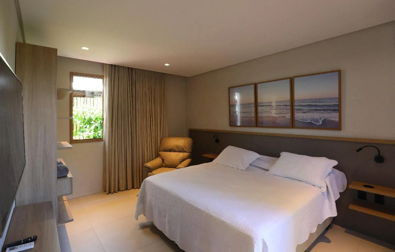 Suíte sóbria com cama de casal e acabamento em madeira